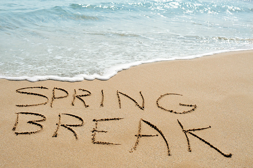 the text spring break written in the sand of a beach