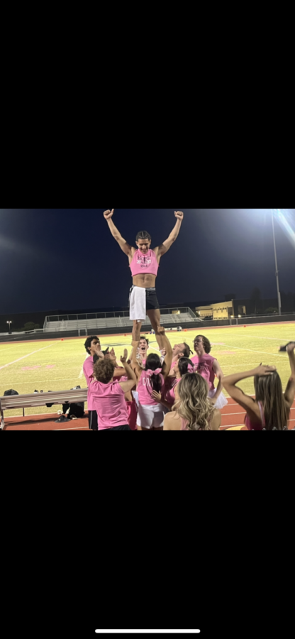 The male cheerleaders lift Angel Santiago while doing a stunt.