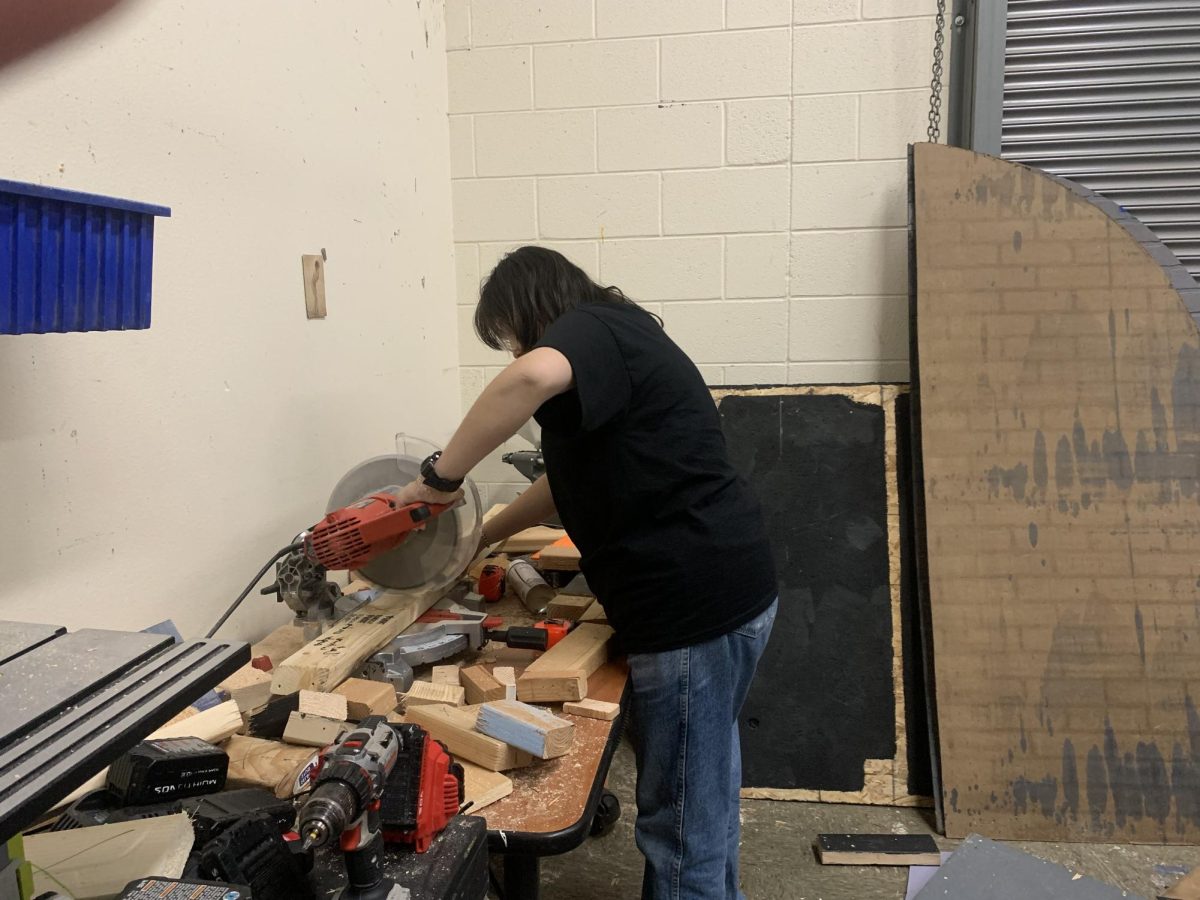 Clara Talker, Stage Manager of Mean Girls, cutting wood for the set.