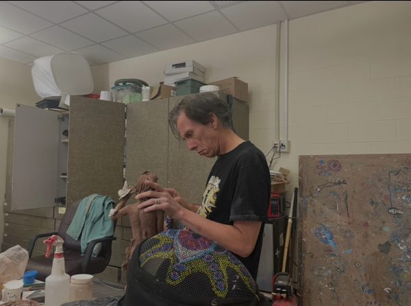 Mr. Brown works on a clay sculpture of a figure holding a butterfly. 