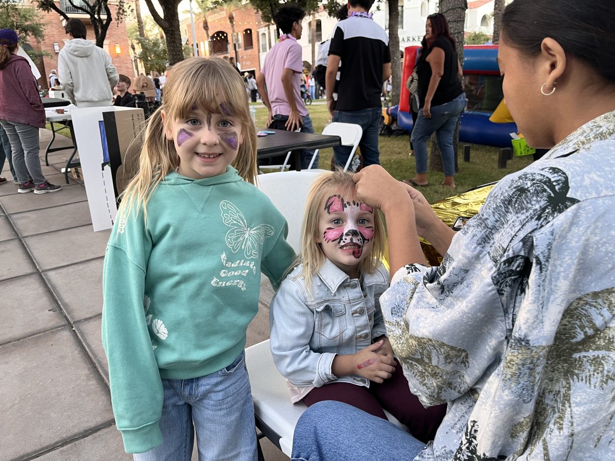 Journalism club offering face paint to the children and students at the block party.