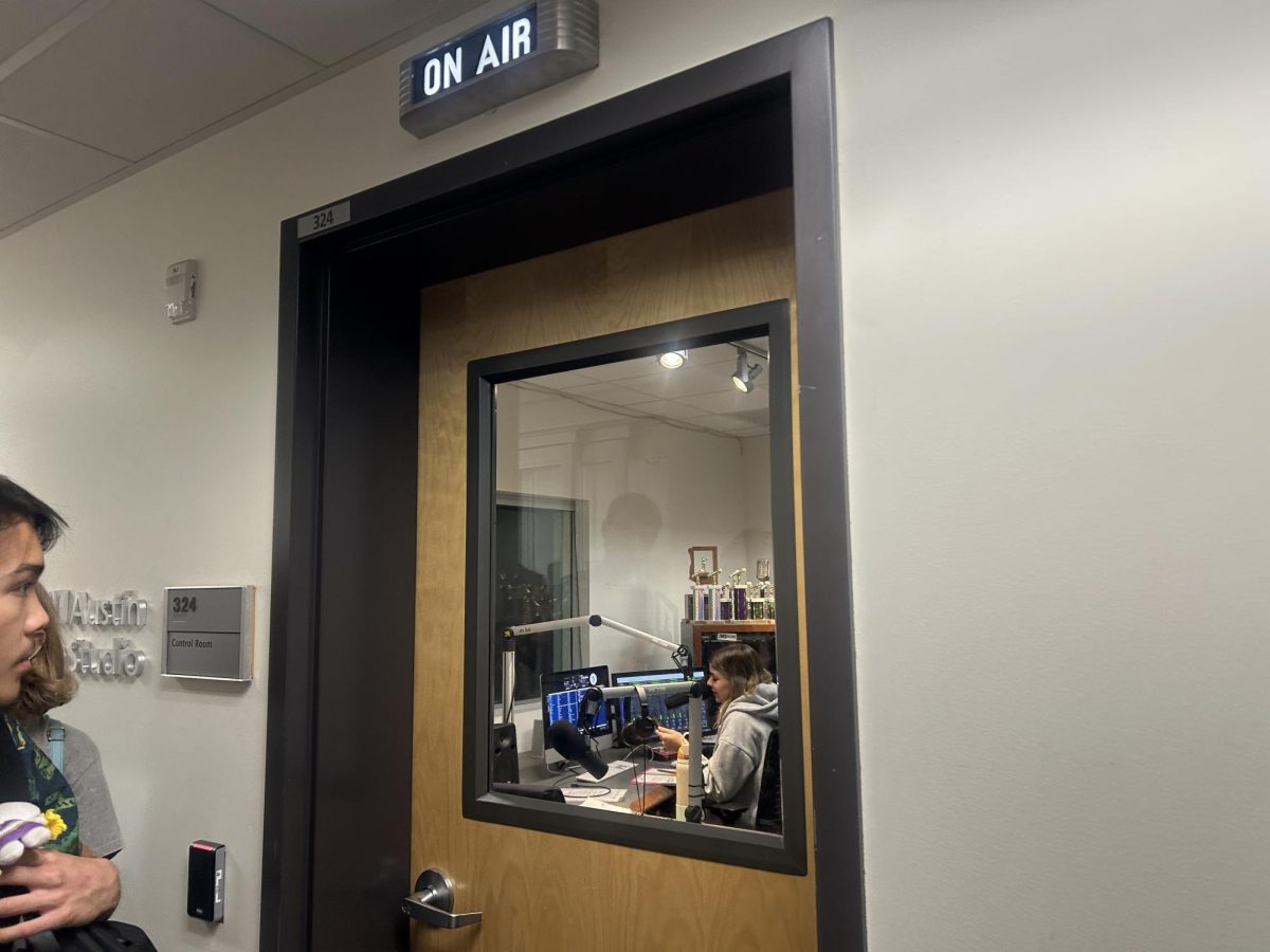 Antonio Larson peers in while a Cronkite student creates their broadcast.