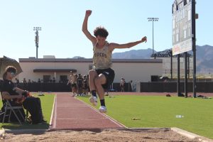 Josiah Presley of the Verrado long jumping team mid-jump, about to impact the sand.