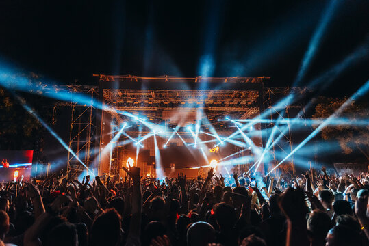 Festivalgoers enjoy the music and dance while lights illuminate above them.